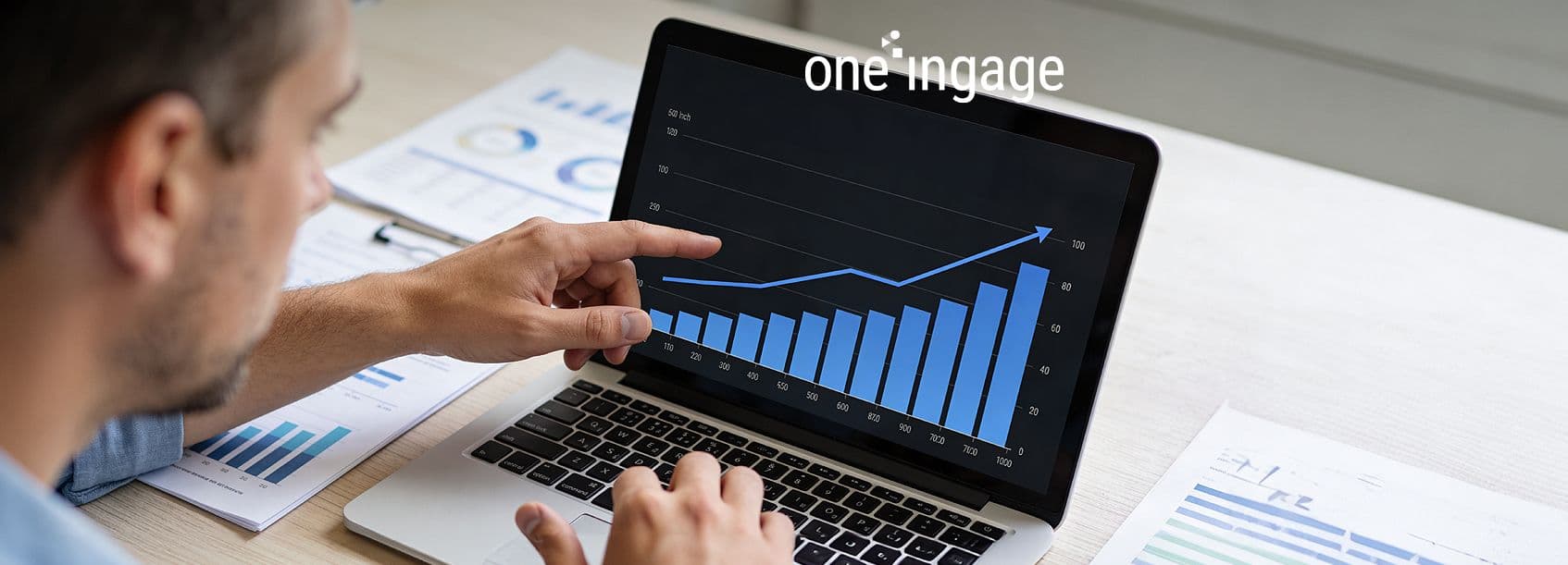 Business colleagues discuss media spend and revenue projections while looking at data on a large screen.